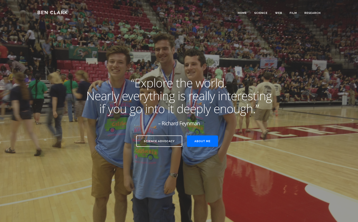 The homepage of my portfolio site: a full-bleed photo of three teenagers in medals on a basketball court, overlaid with a Feynman quote — “Explore the world. Nearly everything is really interesting if you go into it deeply enough.” — and buttons reading Science Advocacy and About Me